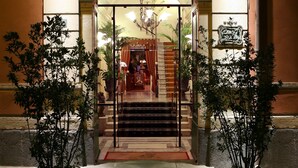 An entrance with a glass door, steps leading up to a balcony, and potted plants on either side. - Liberty Hotel (Catania)