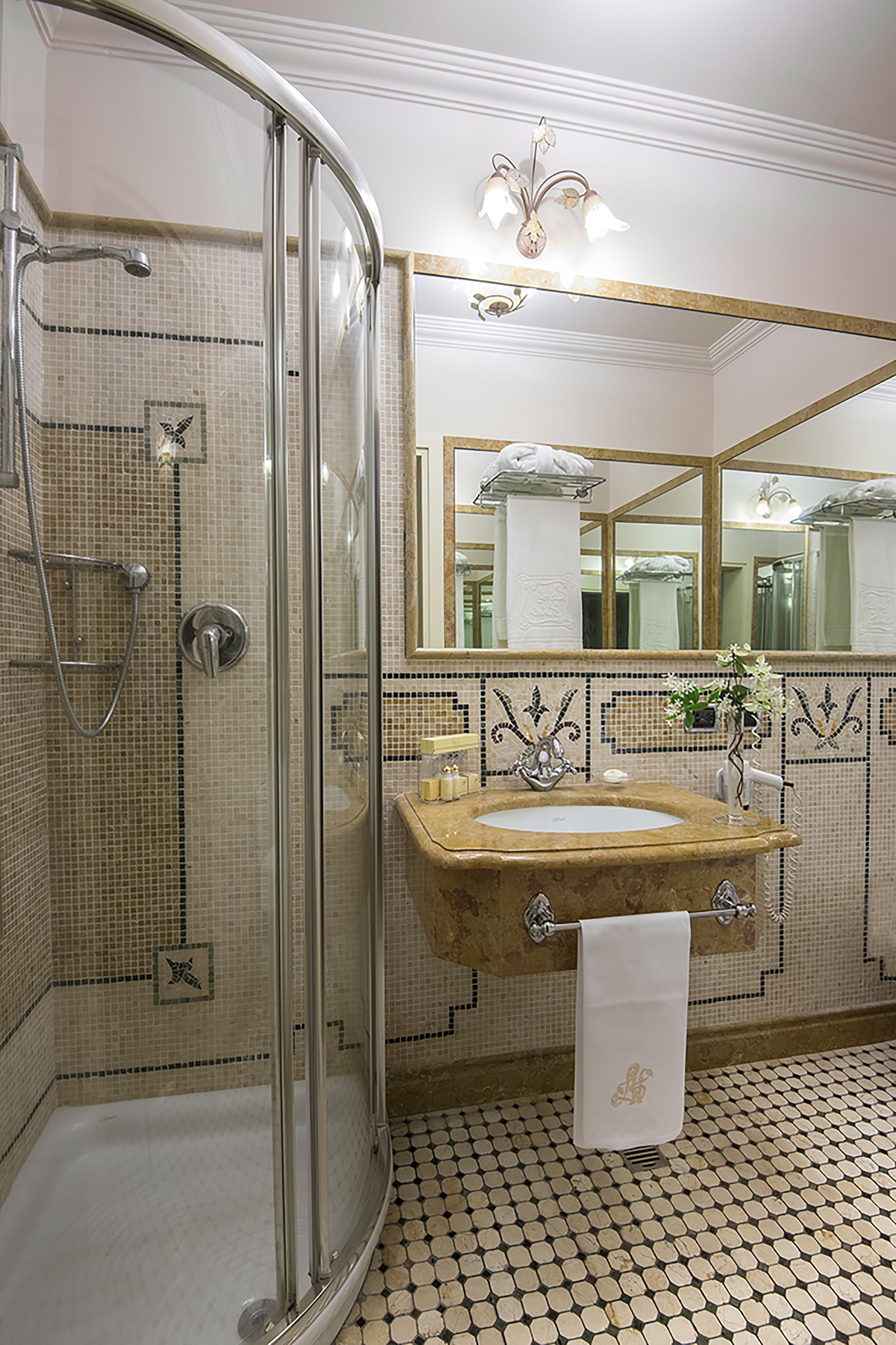 A bathroom with a glass-enclosed shower, a sink with a towel, and a mirror.