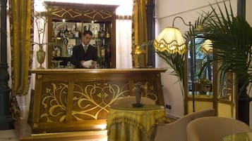 Zona bar con un barista, un tavolo rotondo con una lampada e sedie a fantasia.