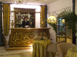 Zona bar con un barista, un tavolo rotondo con una lampada e sedie a fantasia.