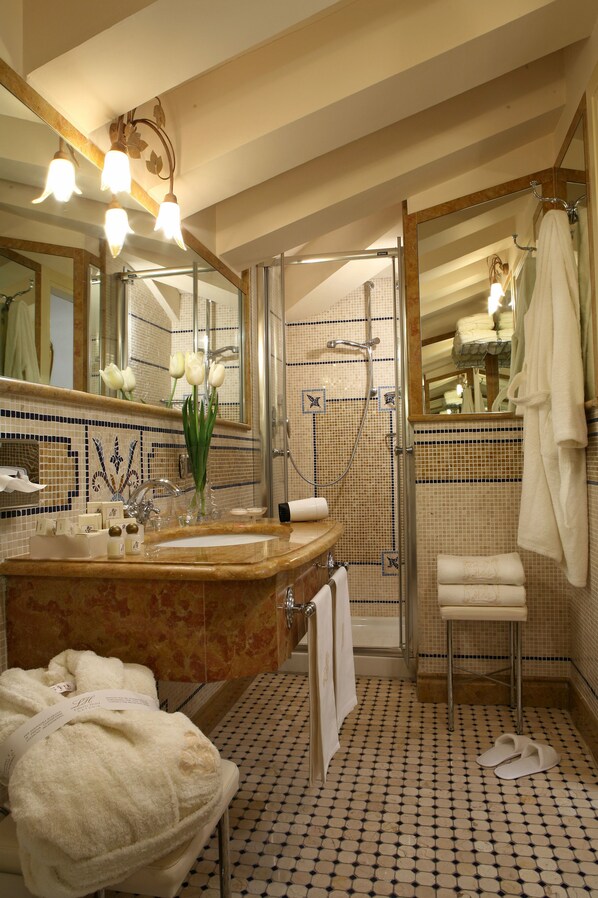 A bathroom with a large mirror, a sink with a vase of flowers, a shower, and a towel rack.