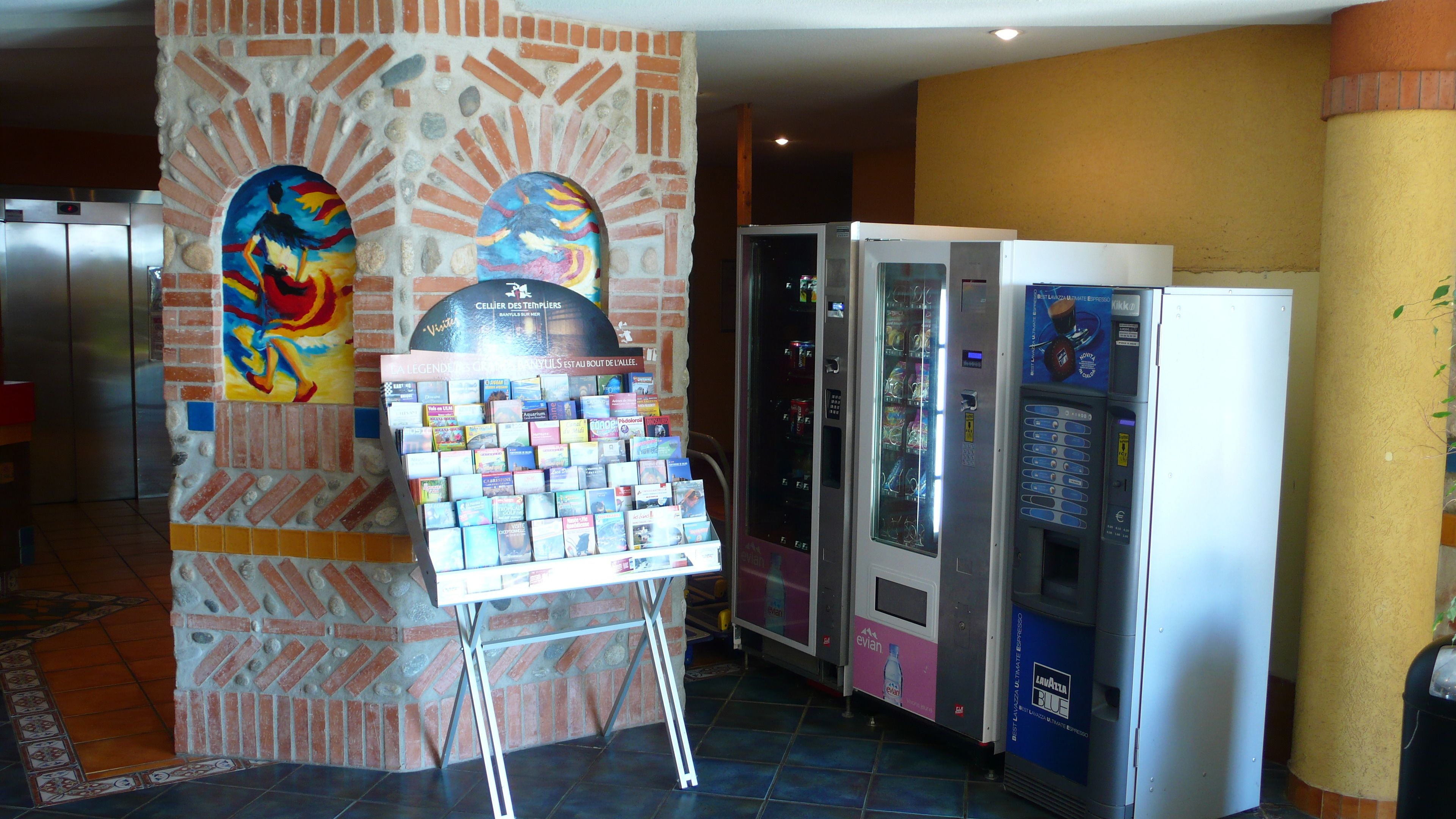 Un vestíbulo con una exhibición de libros, máquinas expendedoras y un pilar con diseño de ladrillo.