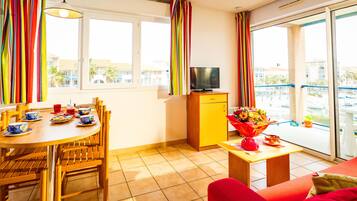 Una sala moderna con comedor, televisor y balcón con vistas a edificios.