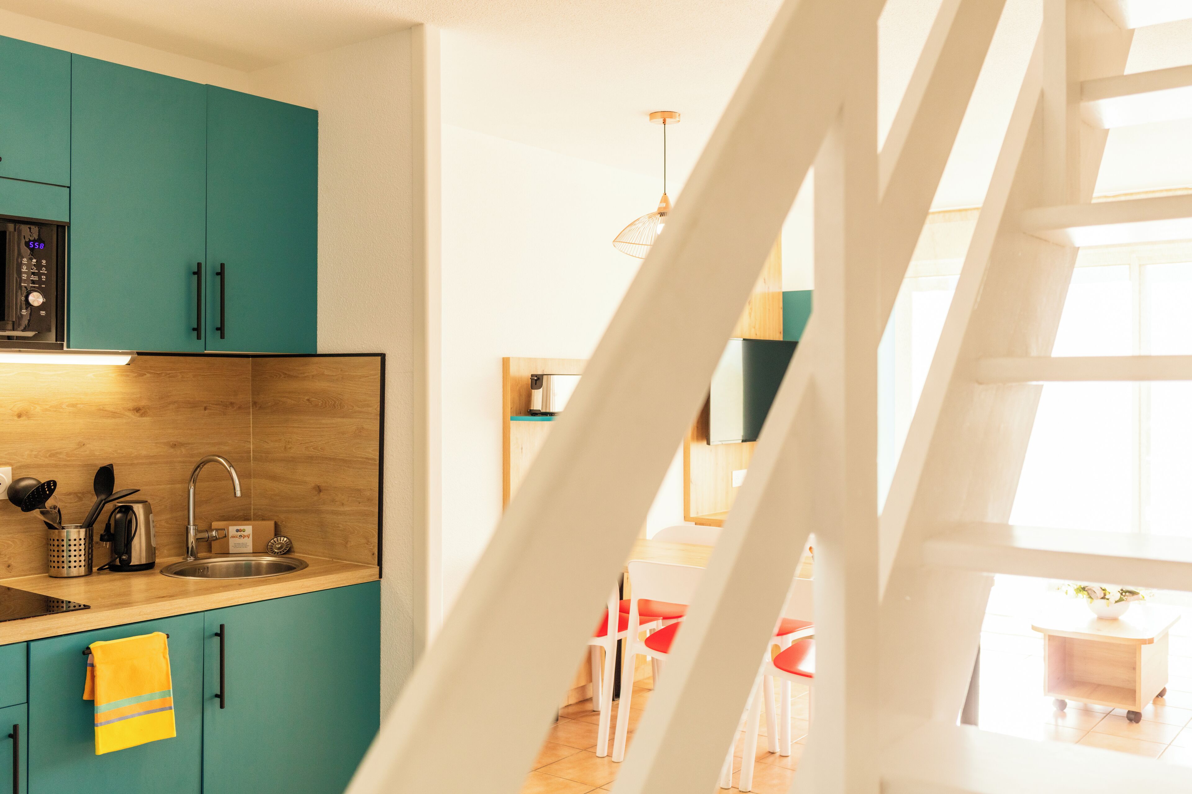 A kitchen with teal cabinets, a wooden countertop, and a sink.