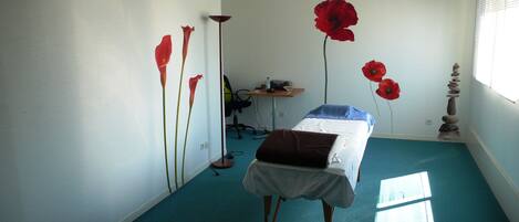 Een kamer met een bed, een bureau, een stoel en een raam met jaloezieën.