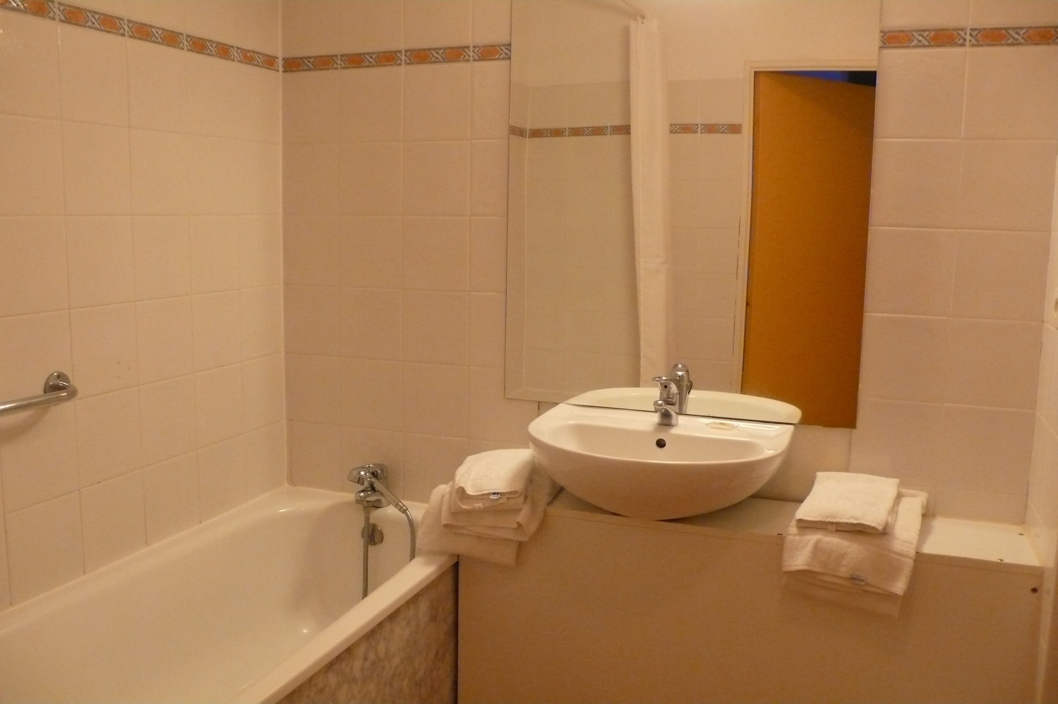 A bathroom with a bathtub, a sink, and a mirror.