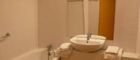 A bathroom with a bathtub, a sink, and a mirror.