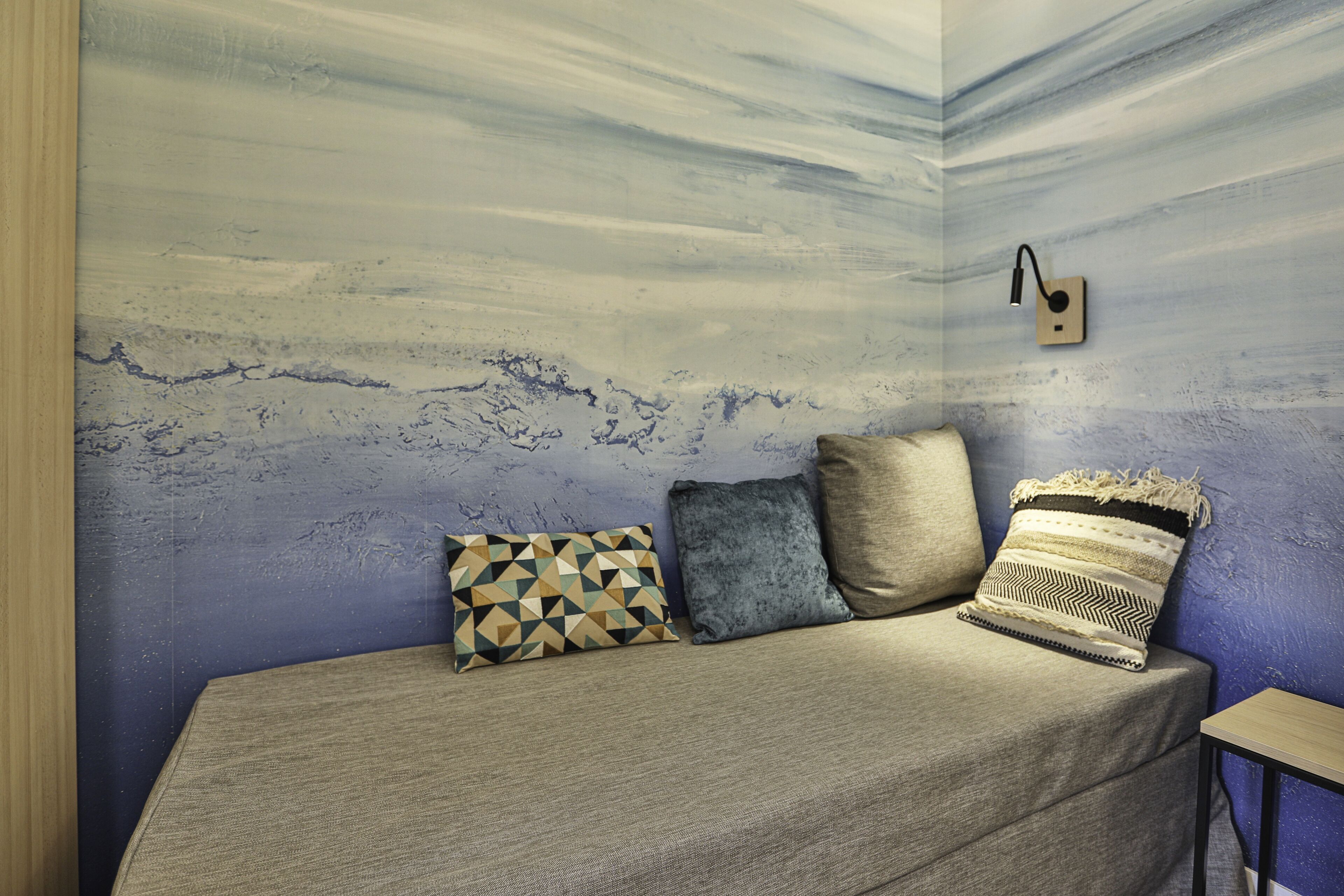 A room with a textured wall, a sofa with patterned cushions, and a small table.
