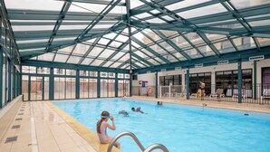 An indoor swimming pool with a glass ceiling, clear poolside area, and a lifeguard chair. - Pierre & Vacances La Rochelle Résidence Centre (La Rochelle)