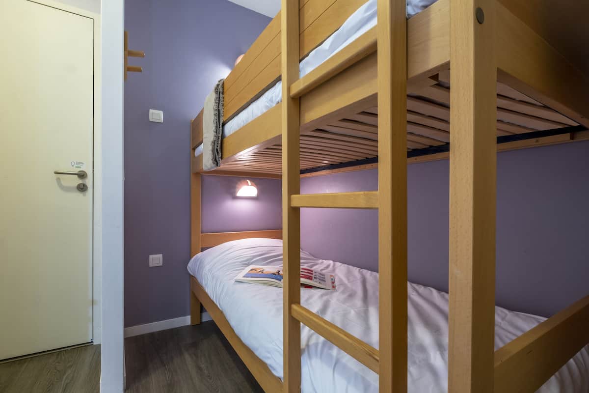 A bunk bed room with a door, light switch, and a small window.