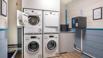 Un cuarto de lavandería con cuatro lavadoras, un calentador de agua y un panel de control.