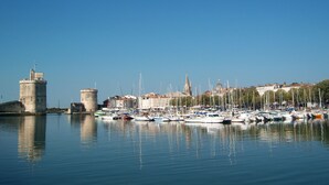 A marina with boats docked, a prominent tower, and a cityscape in the background. - Pierre & Vacances La Rochelle Résidence Centre (La Rochelle)