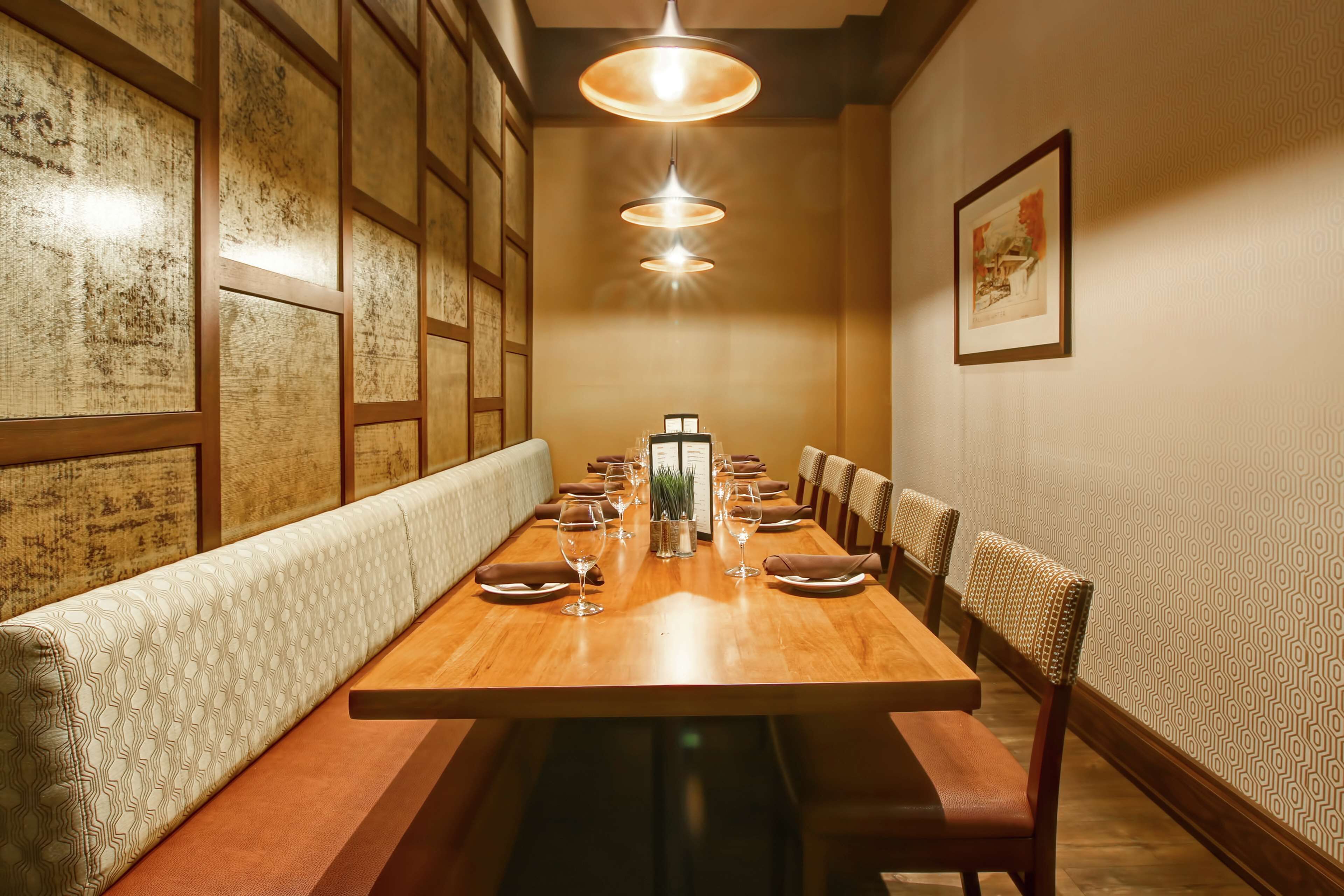 A long dining table with chairs, a bench, and a menu stand in the center.