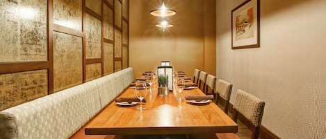 A long dining table with chairs, a bench, and a menu stand in the center.