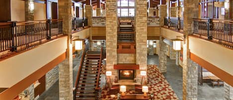 A spacious lobby with a fireplace, multiple levels, and a stone column structure.
