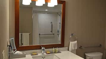 A bathroom with a sink, mirror, and shower.