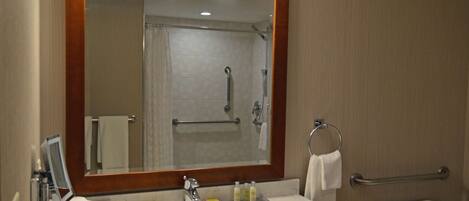 A bathroom with a sink, mirror, and shower.