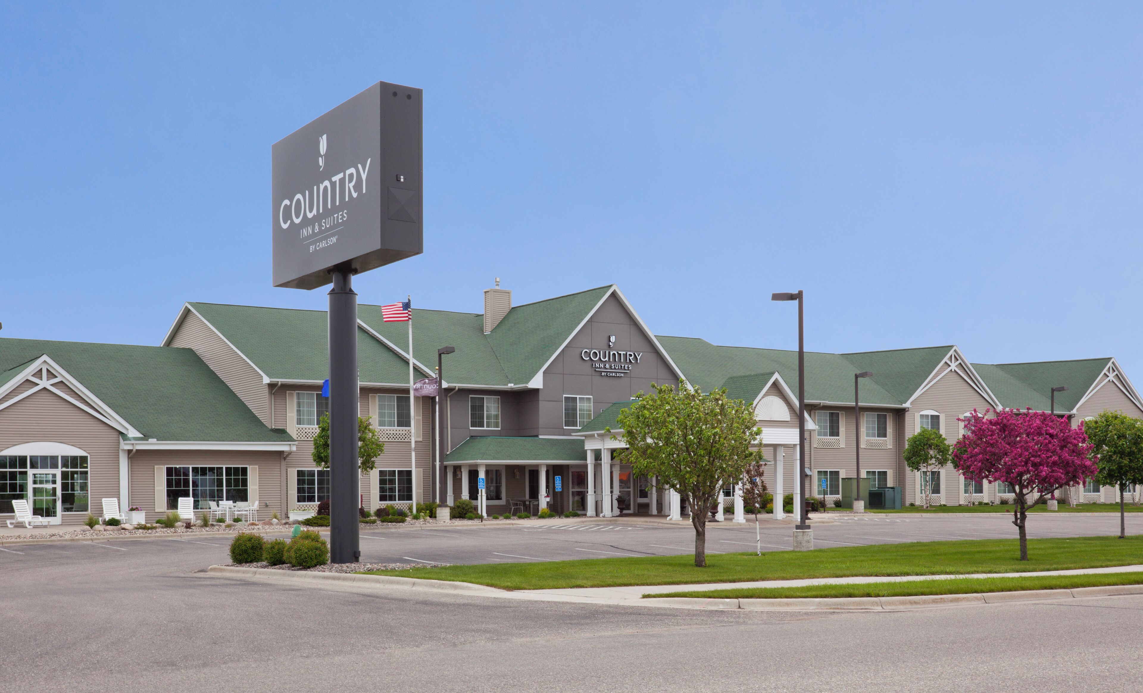 Ein Country Inn & Suites Hotel mit blauem Himmel, einem Parkplatz und einer Flagge.