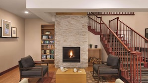A living room with a fireplace, a staircase, and a bookshelf.