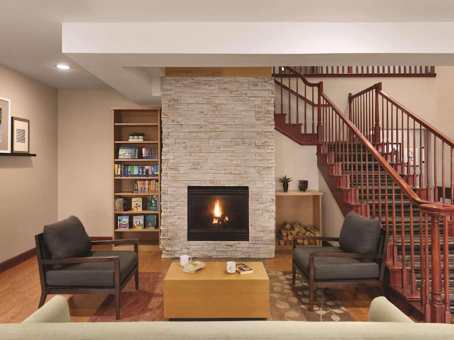 A living room with a fireplace, a staircase, and a bookshelf.