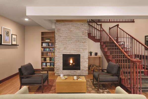 Una sala de estar con chimenea, una escalera y una estantería.