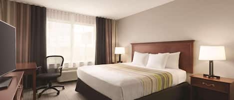 Habitación de hotel con una cama grande, dos lámparas de noche, un escritorio con una silla y un televisor.