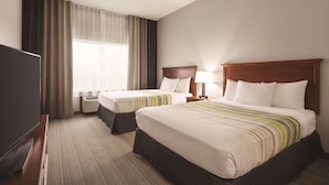 A hotel room with two beds, a TV, and a window with curtains.