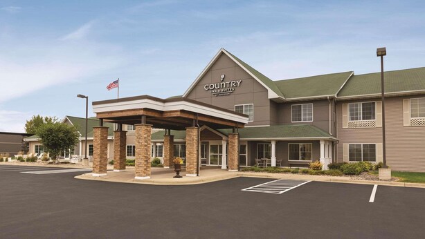 A Country Inn & Suites by Radisson building with a covered entrance, a parking lot, and an American flag.
