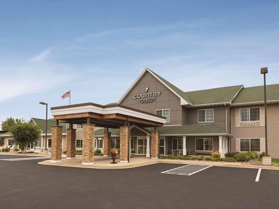 A Country Inn & Suites by Radisson building with a covered entrance, a parking lot, and an American flag.