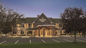 A Country Inn & Suites by Radisson building with a prominent entrance, parking lot, and surrounding greenery.