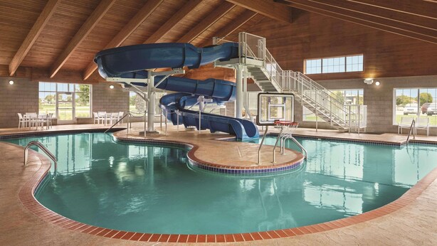 An indoor swimming pool with a multi-level water slide and a staircase leading to a viewing platform.