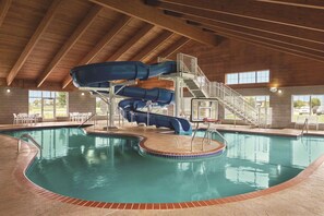 An indoor swimming pool with a multi-level water slide and a staircase leading to a viewing platform.