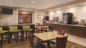 A hotel lobby with a bar area, seating, and a kitchen counter.