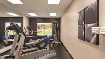 Et fitnesscenter med løbebånd, træningsbolde og styrkemaskiner.