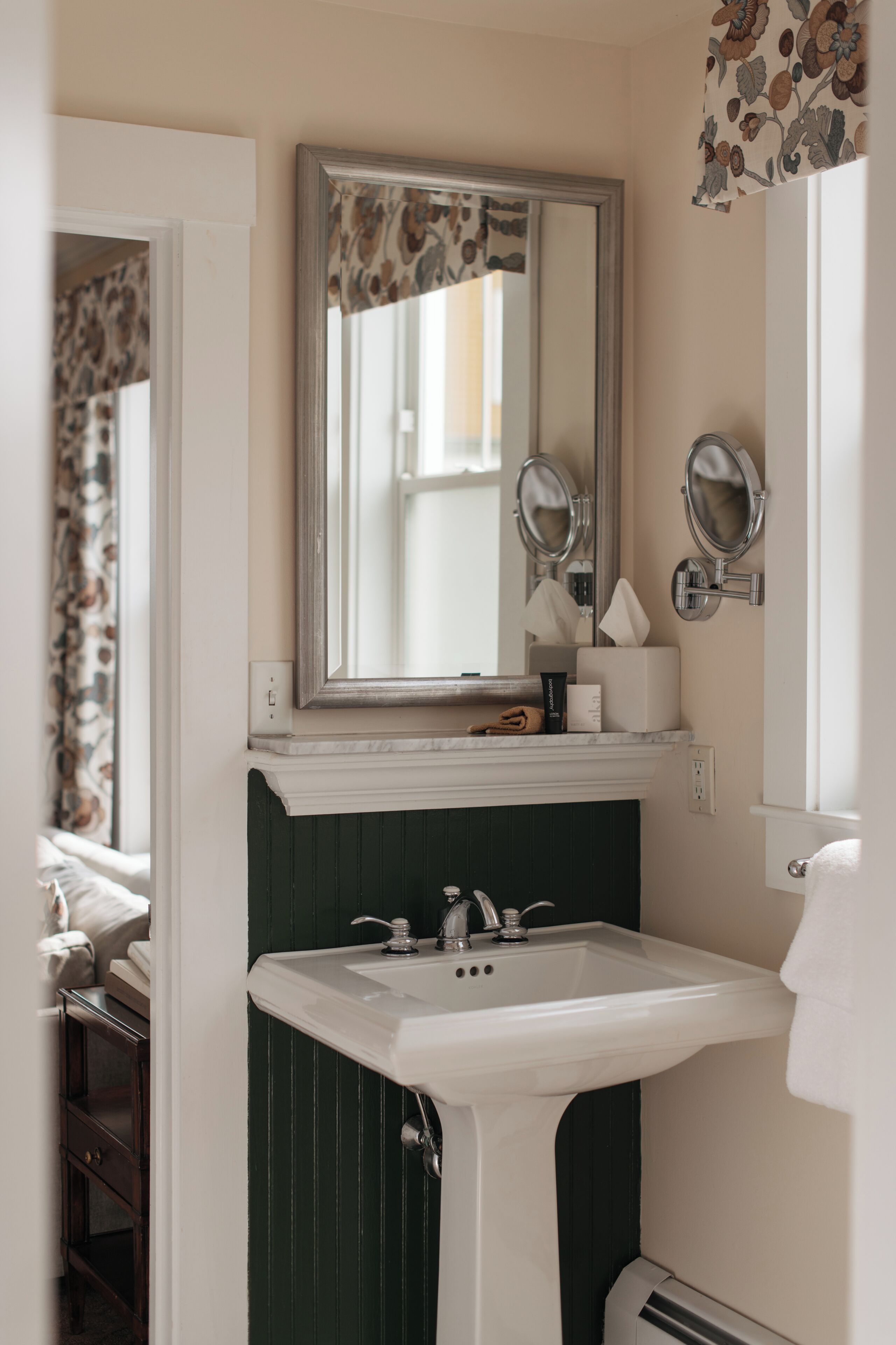 A bathroom with a white sink, green vanity, and a mirror above it.