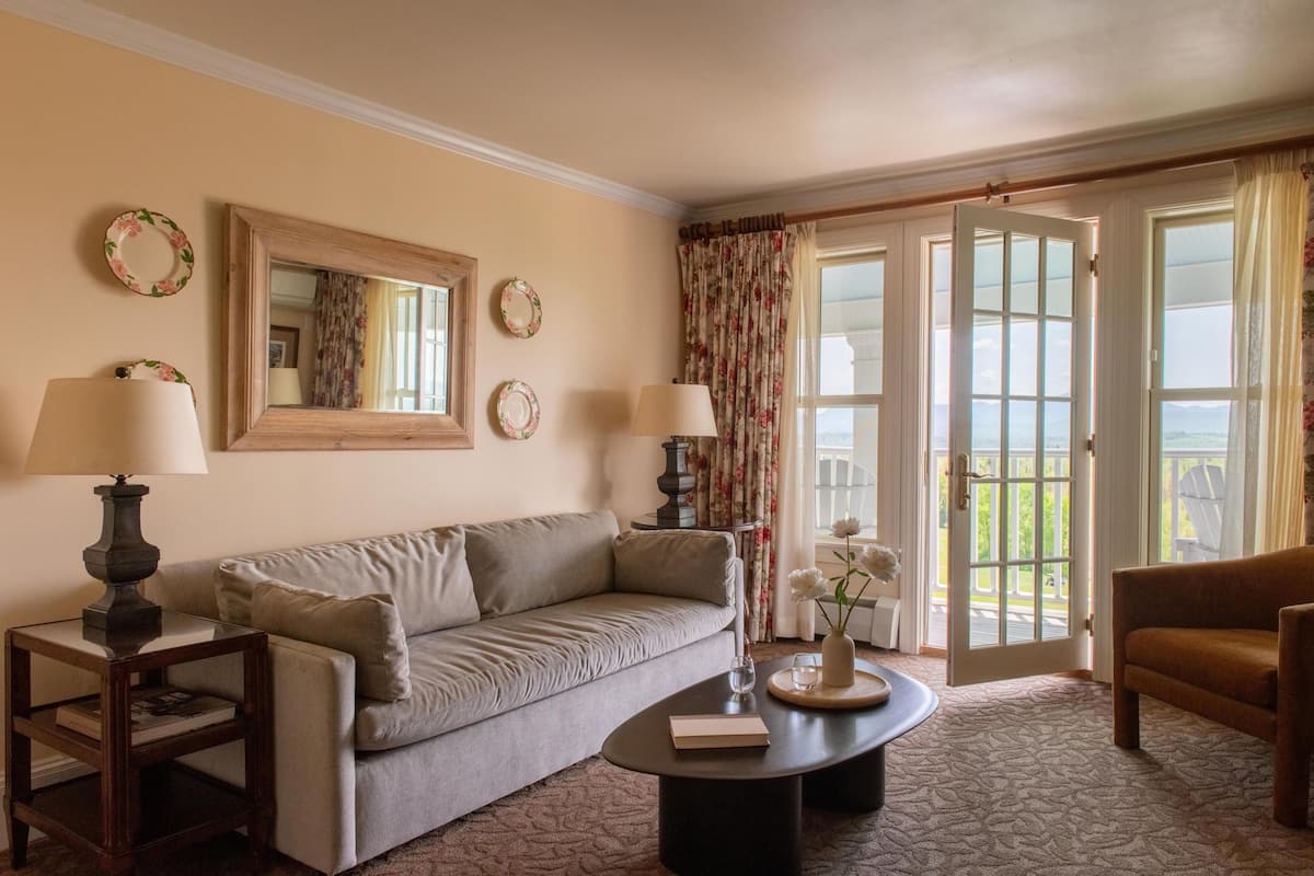 A living room with a sofa, coffee table, lamps, and a door leading to a balcony.