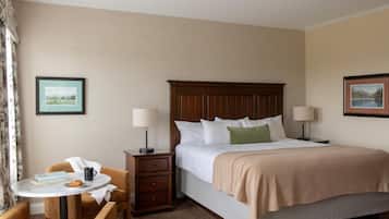 Ein Hotelzimmer mit Bett, Nachttischen, einem kleinen runden Tisch mit Stuhl und zwei gerahmten Bildern an den Wänden.