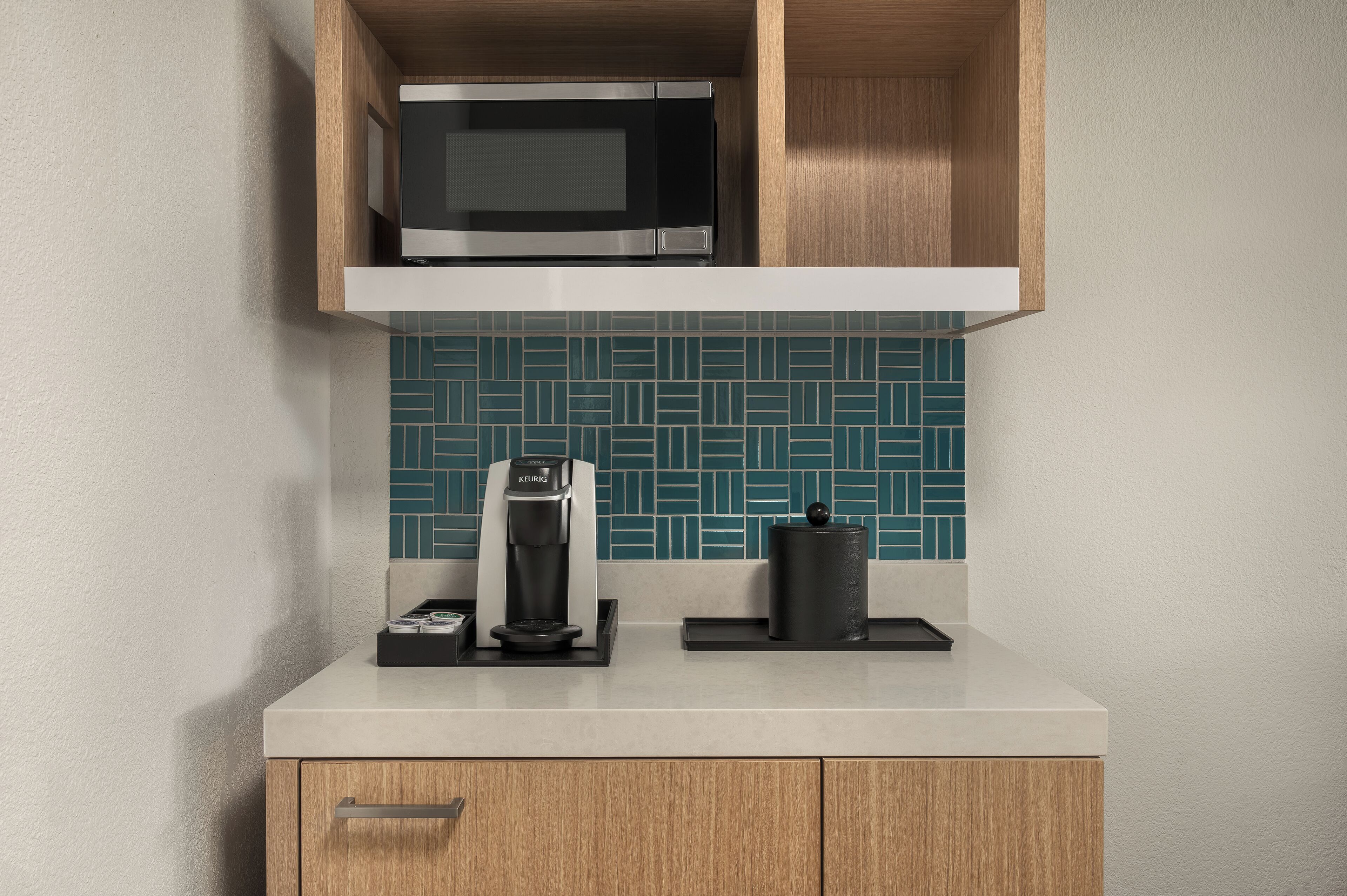 A kitchen with a microwave, coffee maker, and a kettle on the countertop.