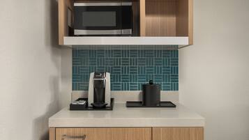 A kitchen with a microwave, coffee maker, and a kettle on the countertop.