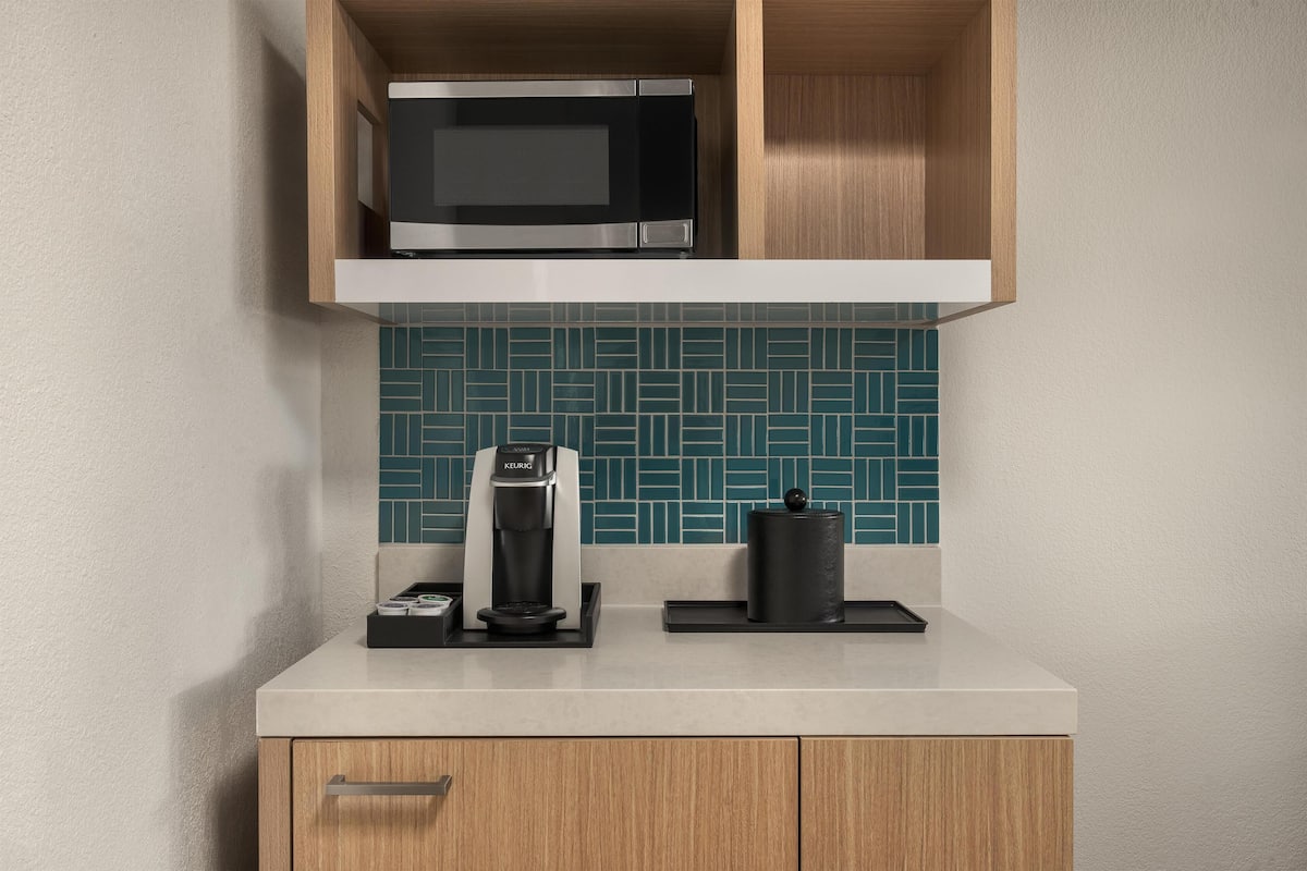 A kitchen with a microwave, coffee maker, and a coffee pot on the counter.