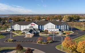 A large, multi-story hotel with a prominent Hilton Garden Inn sign, a central courtyard, and a parking lot.
