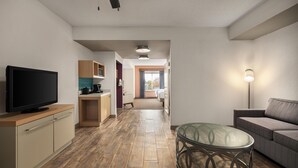 A modern living room with a flat-screen TV, a glass coffee table, and a sofa. - Hilton Garden Inn Wooster (Wooster)