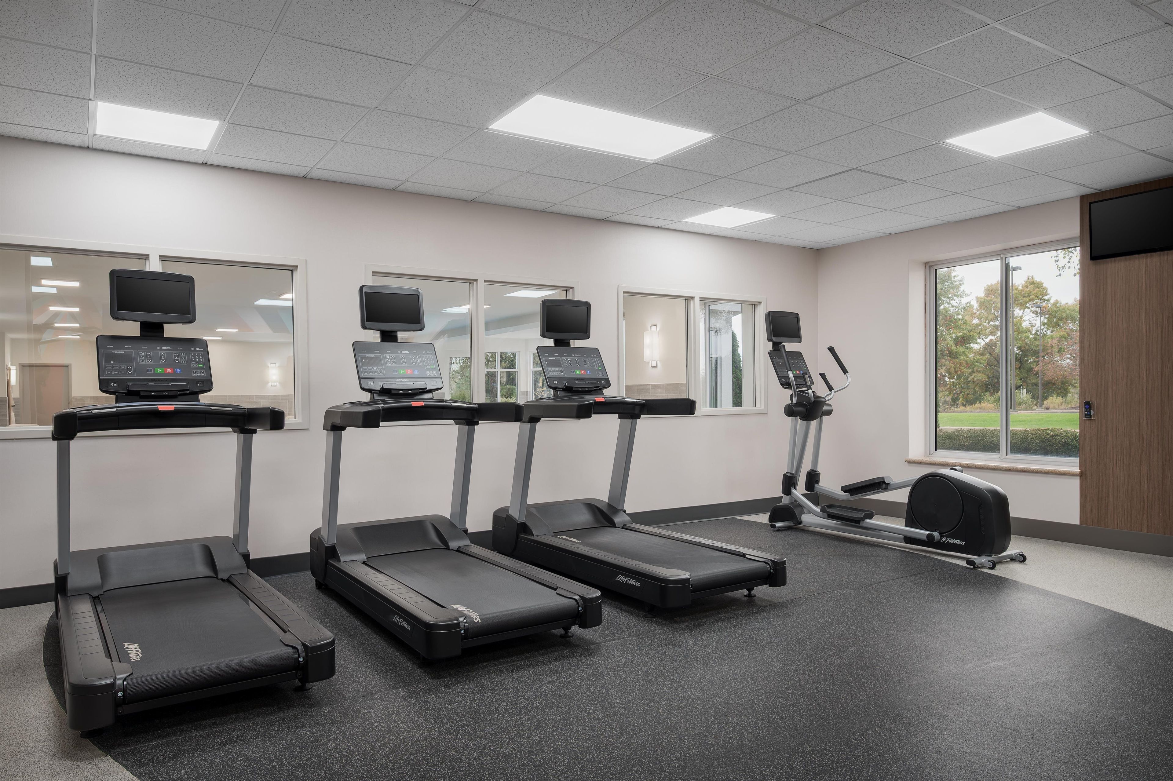 A fitness room with treadmills, a stationary bike, and a rowing machine.