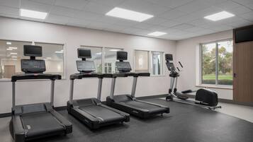 A fitness room with treadmills, a stationary bike, and a rowing machine.