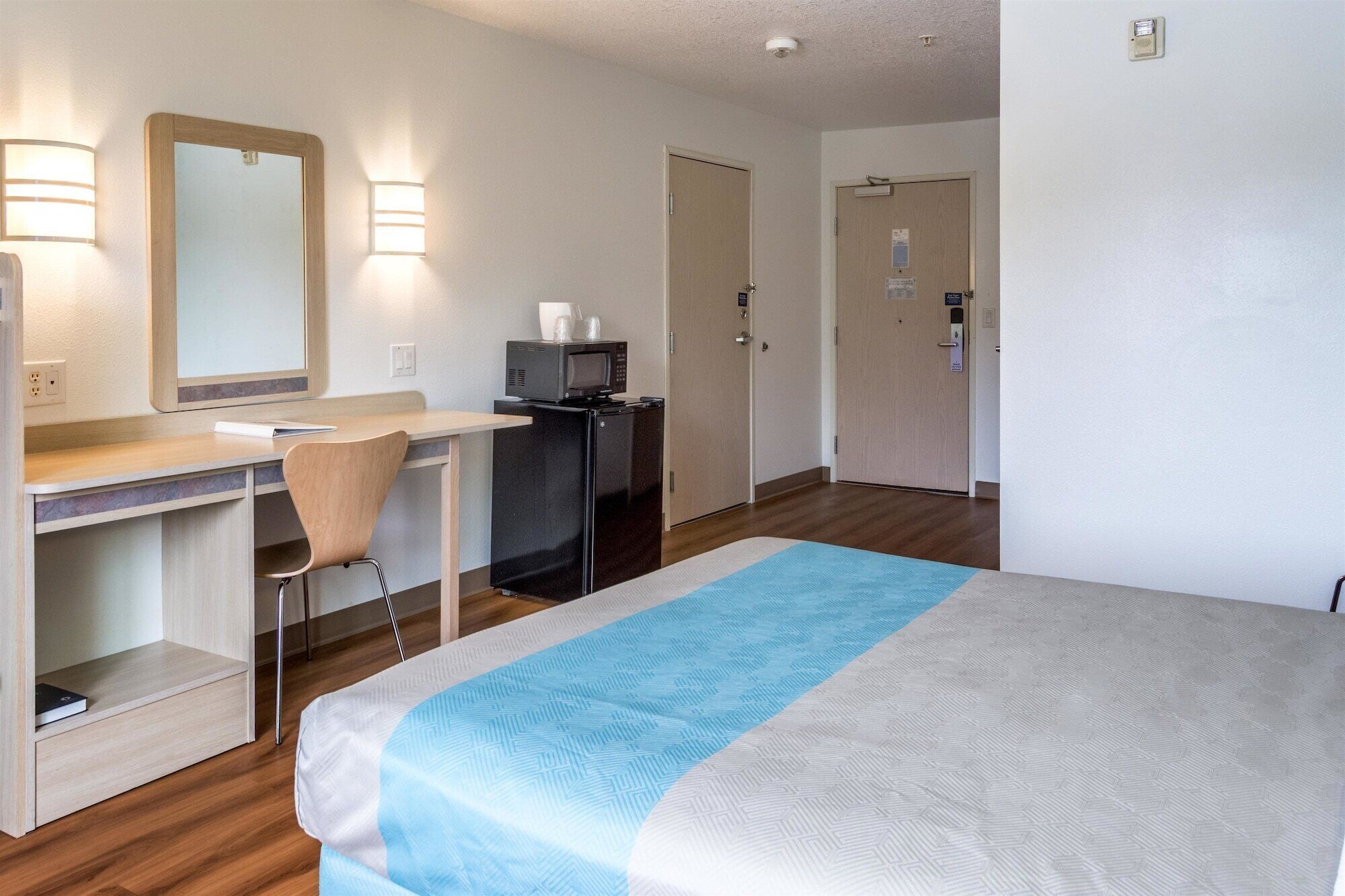 Ein Hotelzimmer mit Bett, Schreibtisch, Stuhl und einer Mikrowelle.