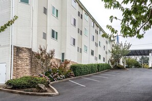 Ein mehrstöckiges Hotel mit Parkplatz und überdachtem Gang.