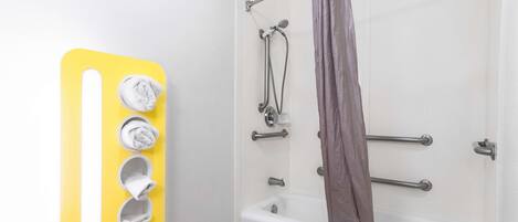 Une salle de bain équipée d’une baignoire, d’une douche avec des barres d’appui et d’un porte-serviettes avec des serviettes.