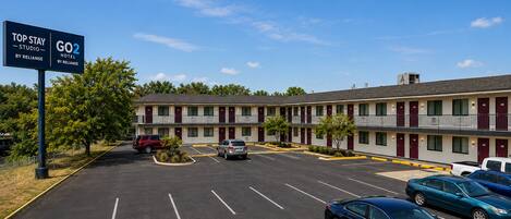 A motel with multiple rooms, a parking lot, and a sign indicating the name and amenities.