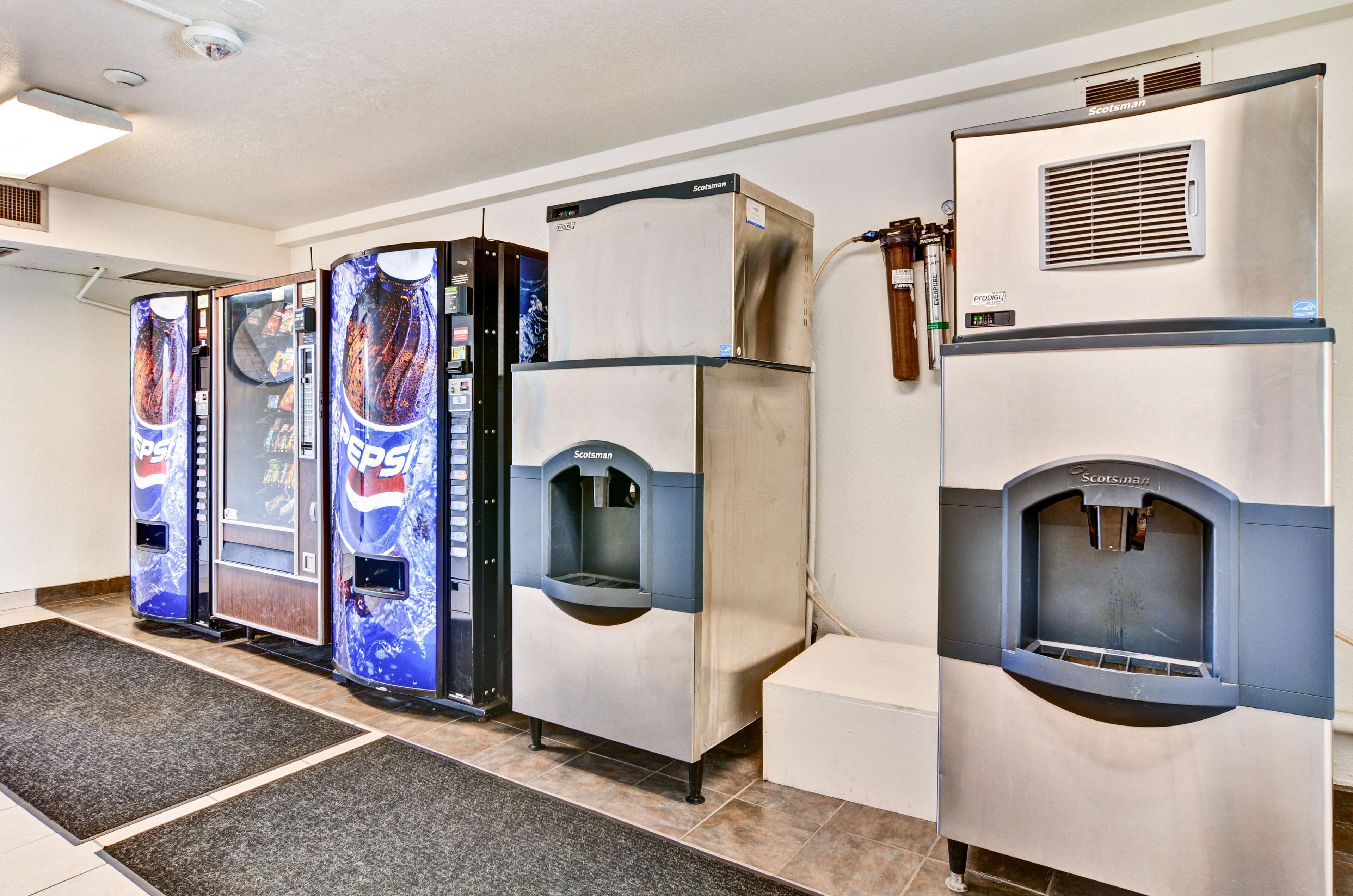 A row of vending machines and a refrigerator in a commercial setting.