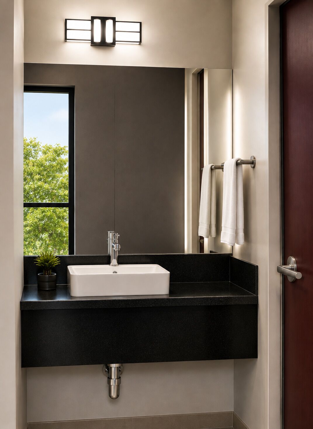 A modern bathroom with a large mirror, a white sink, and a black countertop.